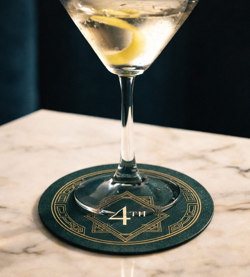 Fourth Floor cocktail bar branding: martini with a lemon twist on a green coaster with gold art deco detailing